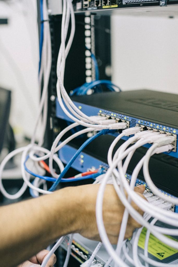 An IT professional configuring network cables in a server rack, focusing on Ethernet connections.